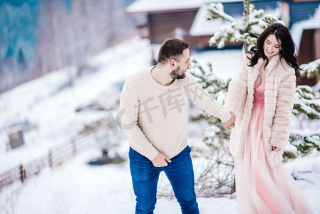 未婚夫摄影照片_穿着毛皮大衣的新娘和未婚夫在喀尔巴底山脉之间