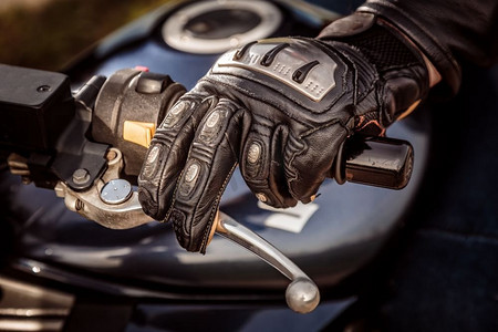 摩托车赛车手套中的人手握住摩托车的油门控制。防止跌倒和意外事故的手部保护。