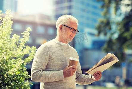 大众媒体、新闻和人物概念—在城市里读报纸喝咖啡的老年人。一位老人在看报纸喝咖啡