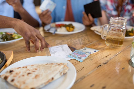 休闲、饮食和支付概念--男性手持账单、金钱或小费放在餐厅餐桌上。男的手拿着餐桌上的钞票和钱