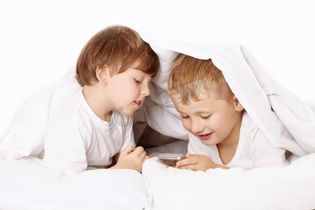 两个小男孩偷偷在毯子下玩手机