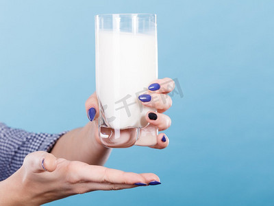 一杯牛奶杯摄影照片_健康饮品，营养好，奶制品理念。女人手里拿着一杯牛奶。女人手拿着牛奶杯