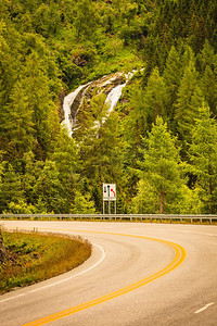 穿过挪威山脉的公路。风景秀丽，绿意盎然，有瀑布。旅游和旅游业..挪威山区的道路景观