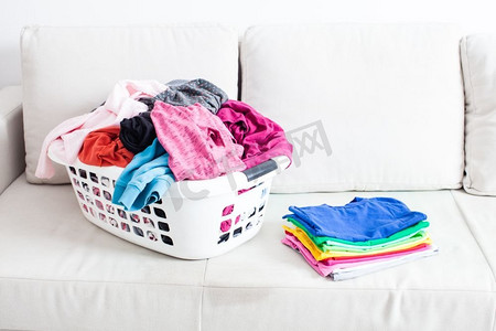 在篮子里洗衣服，在沙发上放一叠干净的亚麻布。五颜六色的干净衣服