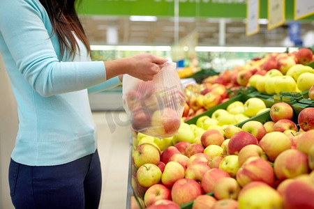 销售、购物、食品、消费主义与人的概念--杂货店里拿着苹果的女人。拿着袋子的女人在杂货店买苹果
