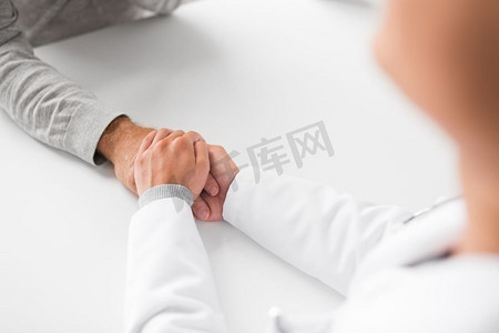 医学，保健和老年概念—年轻医生的特写镜头举行老年病人的手。近摄医生拿着老年病人的手