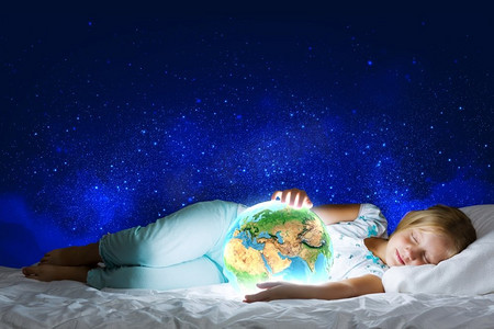 星空晚安海报摄影照片_晚安女孩在床上与地球行星在手中。这张图片的元素是由美国宇航局提供的
