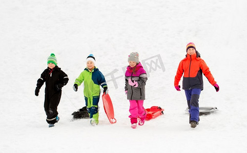 童年、雪橇和季节概念-一群快乐的小朋友在冬天拉雪橇。冬天玩雪橇的快乐小朋友