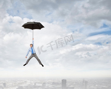 人撑着伞飞。年轻的商人撑着伞在天空中高高飞翔
