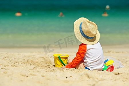 两岁的孩子在沙滩上玩耍。两岁的蹒跚学步的男孩在海滩上玩沙滩玩具 