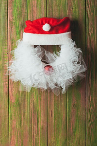 圣诞花环像圣诞老人的头从花边和红色的小玩意的木门。圣诞花环像圣诞老人