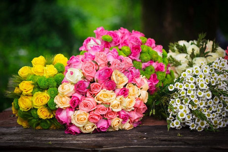 一张木制花店的桌子上放着两束粉色和黄色的玫瑰&S。花店&S餐桌上准备了花束