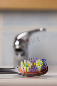 牙齿保健的健康概念。特写镜头刷牙刷在浴室在水槽，水龙头在背景