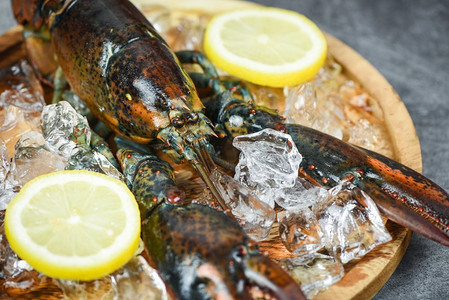 海鲜餐厅的新鲜龙虾贝类熟食/生龙虾加冰和柠檬放在黑色石头桌子上，有选择的重点