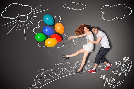 风吹林木摄影照片_幸福的情人节爱情故事概念一对浪漫的情侣拿着随风吹来的气球，背景是粉笔画。