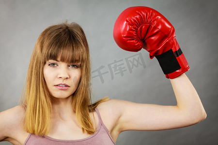 红色励志摄影照片_穿着红色拳击手套的运动女，正在打架。工作室拍摄灰色，背景。戴拳击手套的女人