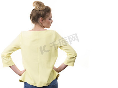 一名成年女子展示了她的休闲美丽服装，从后面穿着长袖黄色上衣。身穿休闲装的女性