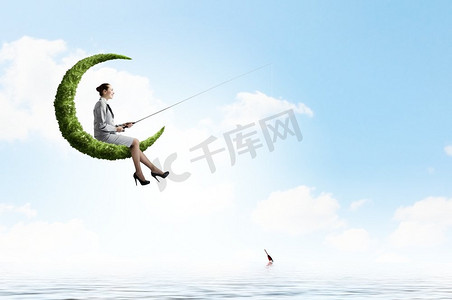 大海月亮摄影照片_钓鱼的概念。女商人在绿色的月亮上用鱼竿钓鱼