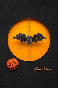 橙色创意背景摄影照片_创意万圣节概念照片，一只蝙蝠用纸做的橙色黑色背景。