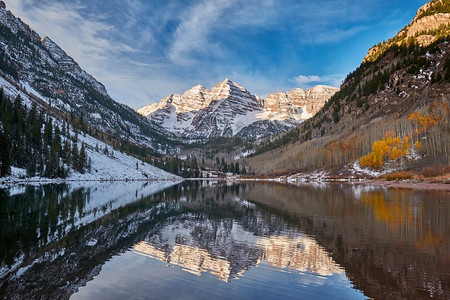 秋天，美国科罗拉多州落基山脉，栗色的钟声和栗色的湖在雪地里倒映着岩石和山脉。
