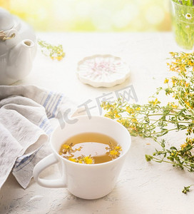 在白色桌子上的草药茶杯在阳光明媚的夏天背景。增强免疫力和消化系统。健康的自然疗法