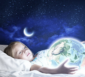 星空晚安海报摄影照片_晚安。女孩躺在床上，手里拿着地球。这张图片的要素由美国宇航局提供