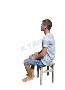 坐在椅子上的沉思的年轻人的侧视图全长肖像和看了离开隔绝在白色背景。