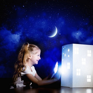 夜里做梦。可爱的小女孩看着房子的模型做梦