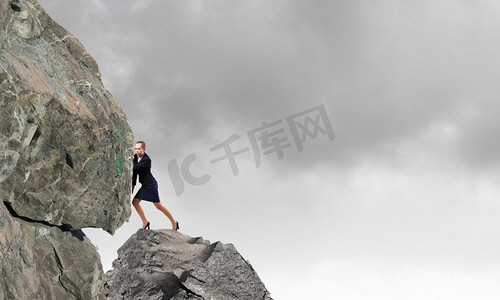 足够精彩摄影照片_一位年轻的女商人正在努力搬运巨石。我有足够的力气做这件事