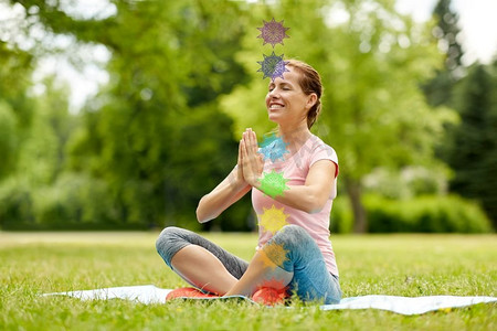 健身，瑜伽和健康的生活方式概念—快乐的女人冥想在夏季公园与七个脉轮符号。快乐的女人冥想在夏季公园