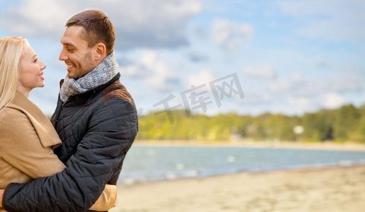 爱情，关系和人的概念-幸福的情侣拥抱着秋日海滩的背景。幸福的情侣在秋天的海滩上拥抱