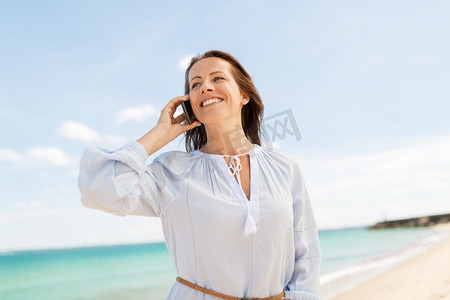 人和休闲概念—愉快的微笑的妇女呼叫智能手机在夏天海滩快乐的女人呼叫智能手机上夏季海滩