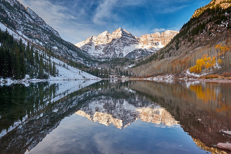 栗色的钟声和栗色的湖与岩石和山在雪周围的反射在秋天在科罗拉多落基山脉，美国。 