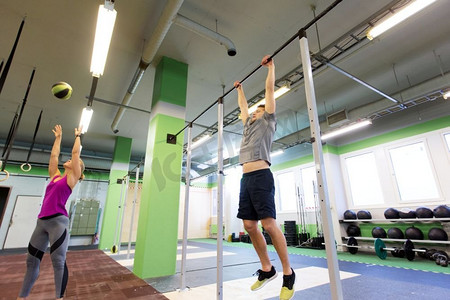 健身、运动和训练理念-男女在健身房进行药球和单杠锻炼。男女在健身房锻炼