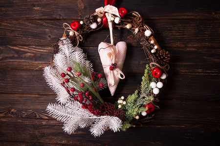圣诞花环摄影照片_红色和白色的圣诞花环。木墙上的圣诞花环。红白元素，纺织心垂