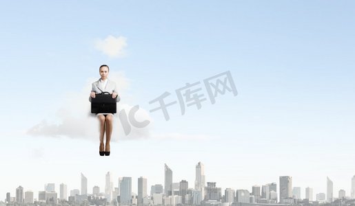 云上的女人。年轻漂亮的女商人坐在城市上空的云端