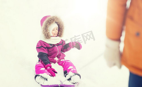 童年，雪橇，时尚，季节和人们的概念-快乐的小孩子在冬天的户外雪橇。冬天坐在雪橇上的快乐小朋友