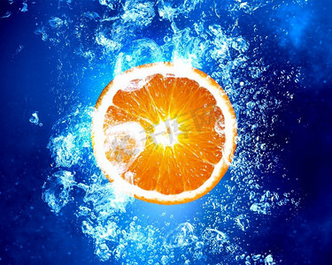 多汁的橙子泡在水里。橙色水果在清澈的蓝色水中飞溅