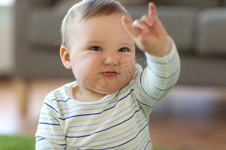 童年，孩子和人的概念-可爱的男婴在家里展示摇滚手势。男婴在家中展示摇滚手的手势