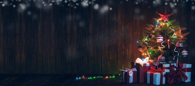 装饰过的圣诞树。装饰圣诞树，木质背景上有发光灯和礼品盒