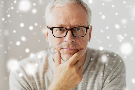 悲伤摄影照片_老年、问题和人的观念--戴眼镜的老人在雪中思考的特写。戴眼镜的老人思考特写