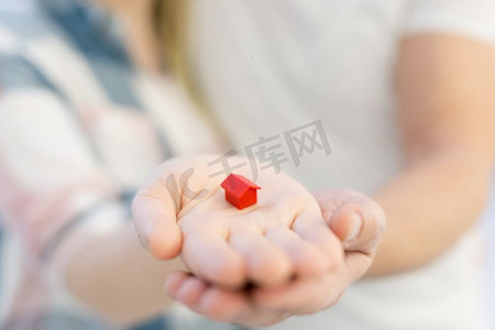 小房子房子摄影照片_拥抱和显示小的红色房子的愉快的夫妇在手中买房子的概念开始家庭