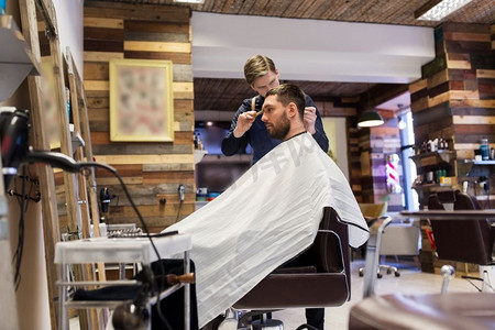 美容、美发和人的概念-理发师和理发师在理发店剪发。一名男子和理发师在理发店理发