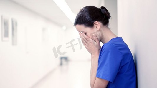 哭泣摄影照片_人、药、保健、忧伤--医院走廊里悲伤或哭泣的女护士。医院走廊里悲伤或哭泣的女护士