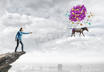 斑马气球摄影照片_斑马上的铅。年轻女子穿着休闲服，斑马在天空中飞翔