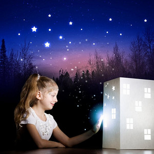 夜里做梦。可爱的小女孩看着房子的模型做梦