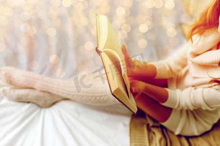 冬天读书摄影照片_冬天、舒适、休闲和人概念-阅读书的少妇关闭在床上在家。近摄年轻女子读书在床上