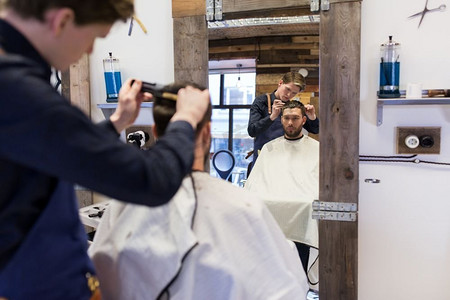 理发、理发和人的概念-理发师和理发师在理发店理发。一名男子和理发师在理发店理发
