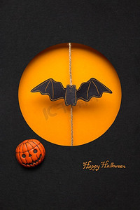 创意万圣节概念照片，一只蝙蝠用纸做的橙色黑色背景。