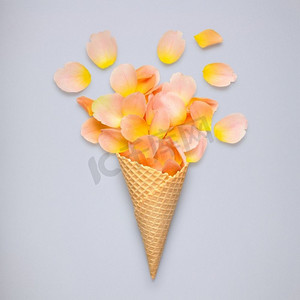 玫瑰创意设计摄影照片_富有创意的静物冰激凌华夫饼蛋卷，灰色背景上有玫瑰花瓣。